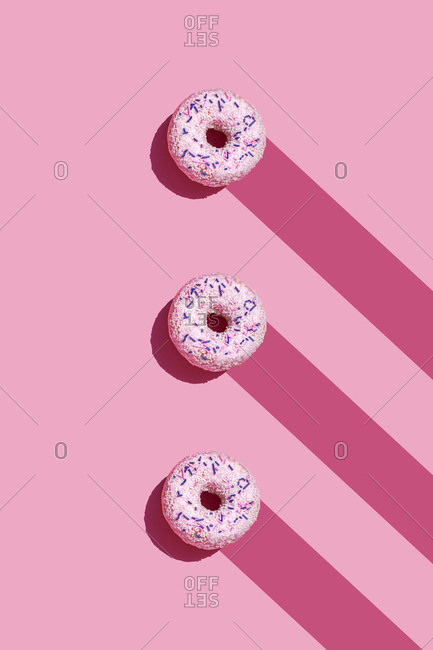 Studio shot of three sweet doughnuts with sugar sprinkles