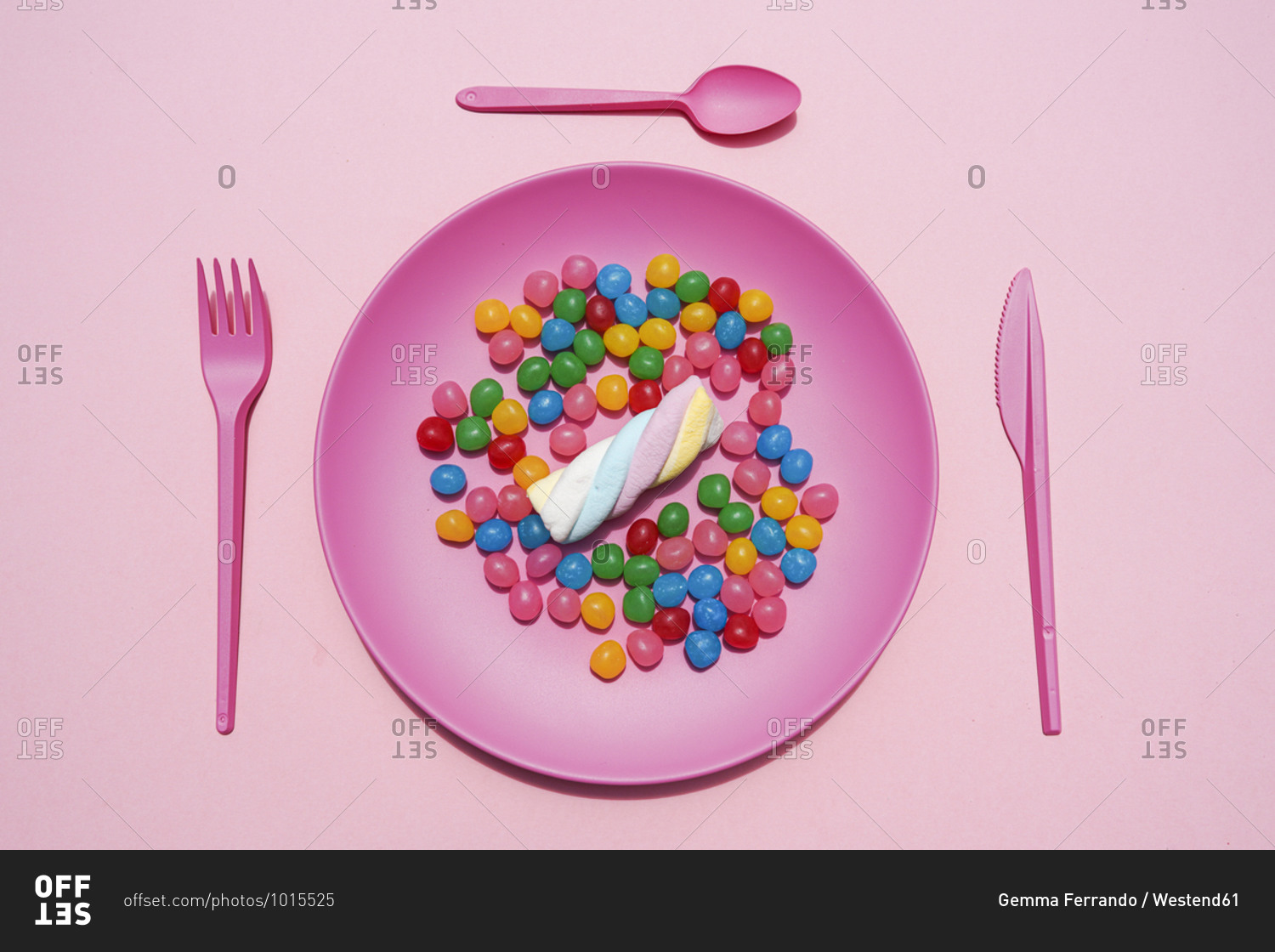 Studio shot of plastic plate full of candies and single marshmallow
