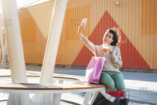 Pretty woman clicking selfie while sipping juice at shopping mall