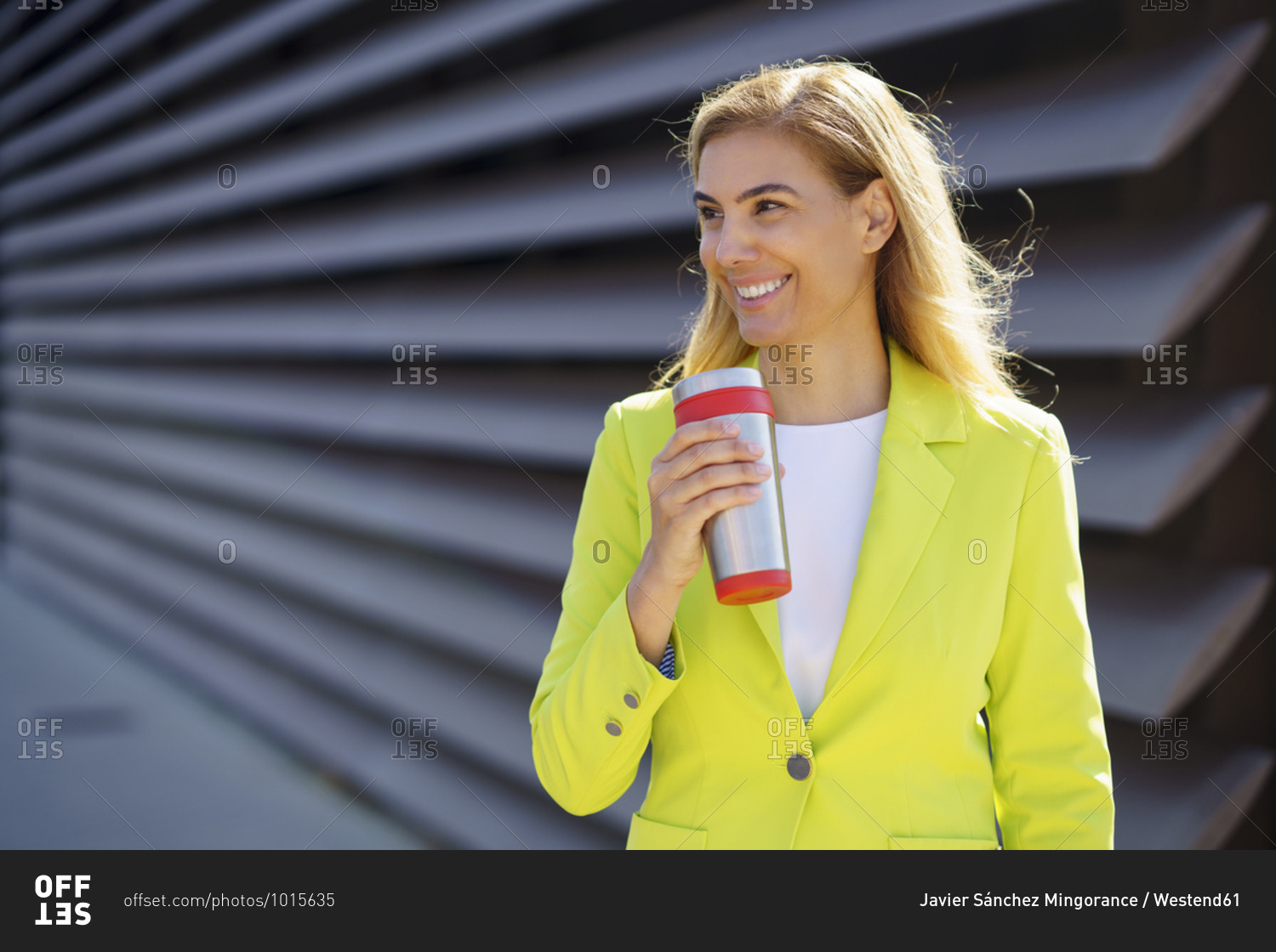 Smiling mature businesswoman with travel mug looking away