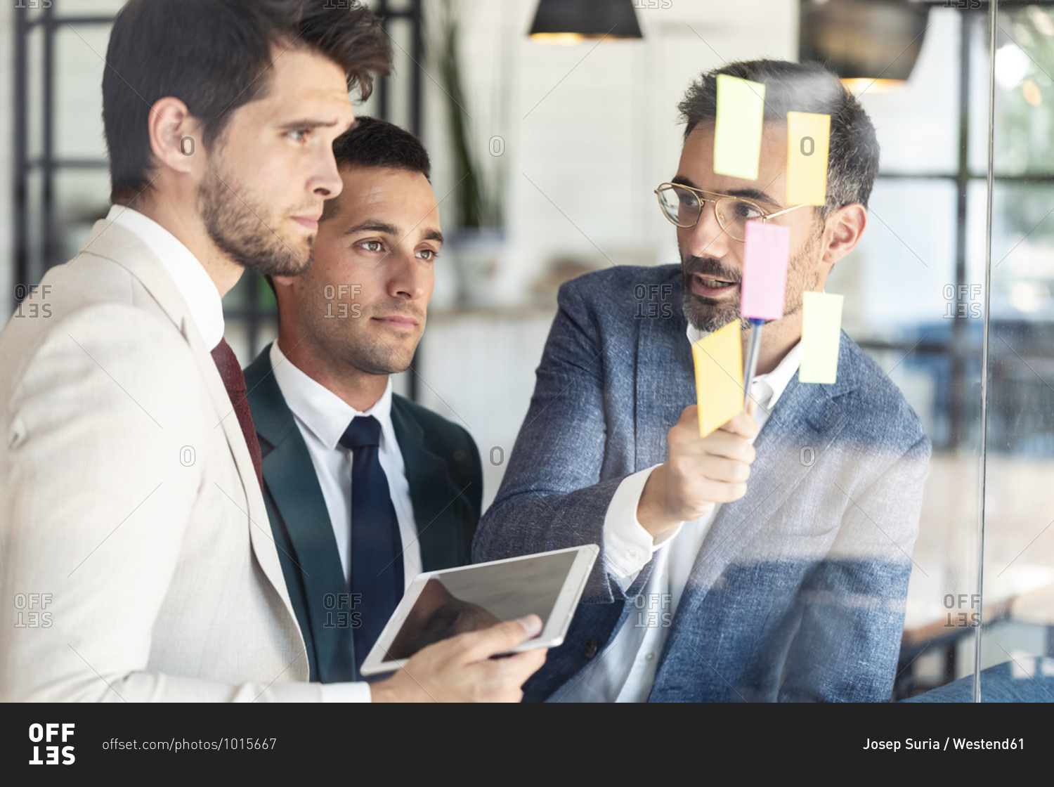 Businessman explaining coworkers over sticky notes during meeting