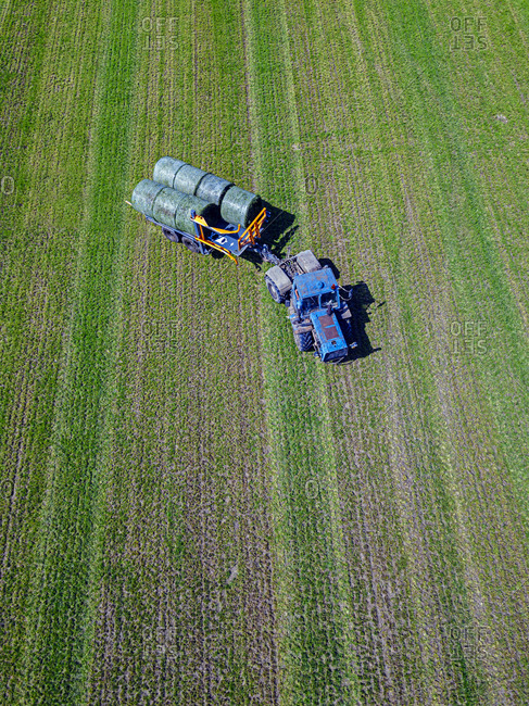 Aerial view of tractor collecting hay bales in field