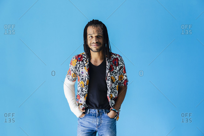 Man with fractured arm standing against blue background
