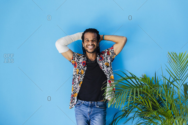 Smiling man with fractured arm posing against blue background
