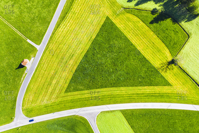 Germany- Bavaria- Hopferau- Drone view of Kapelle Saint Antonius and triangle shaped field in spring