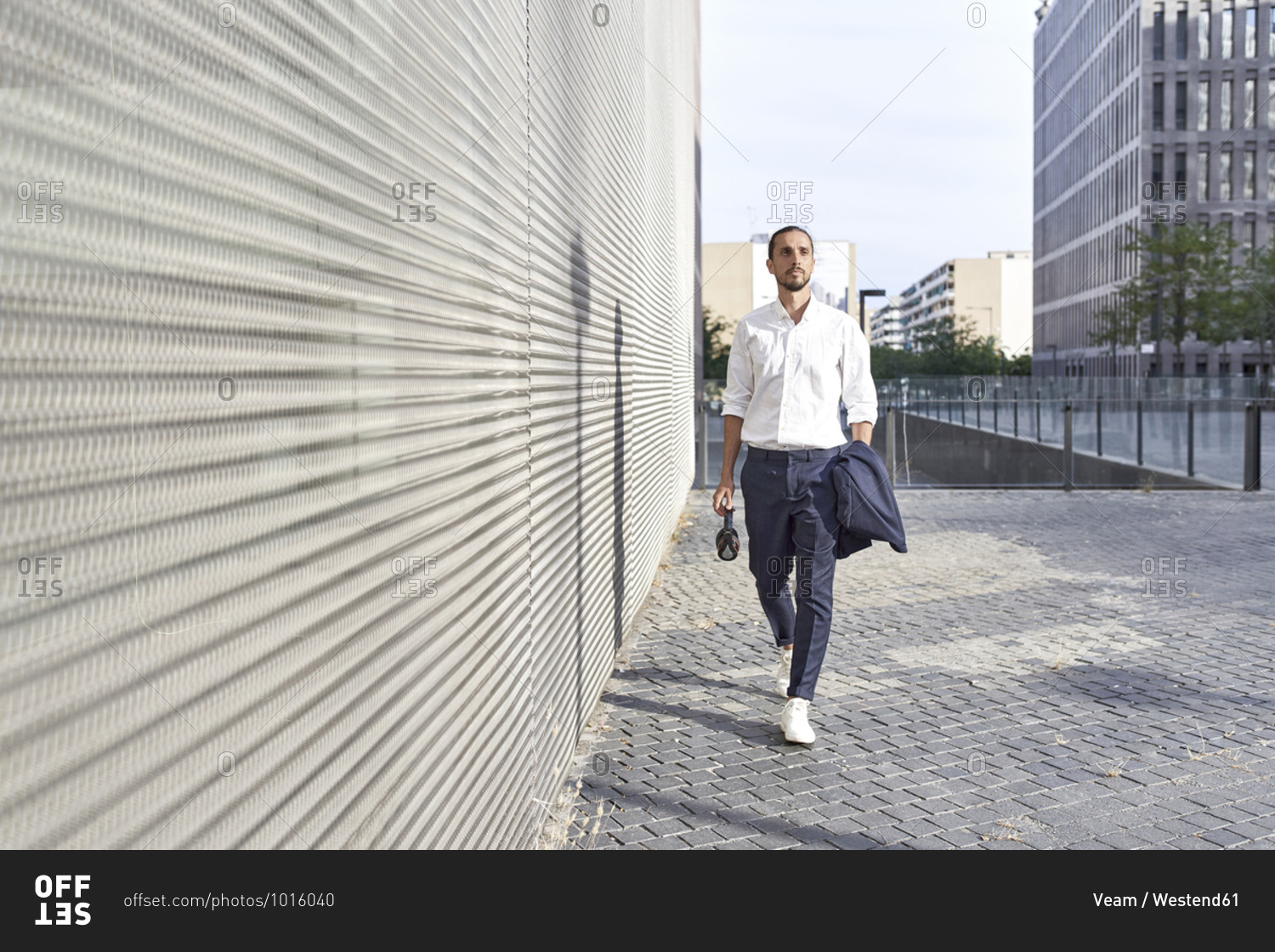 Businessman with headphones walking in city