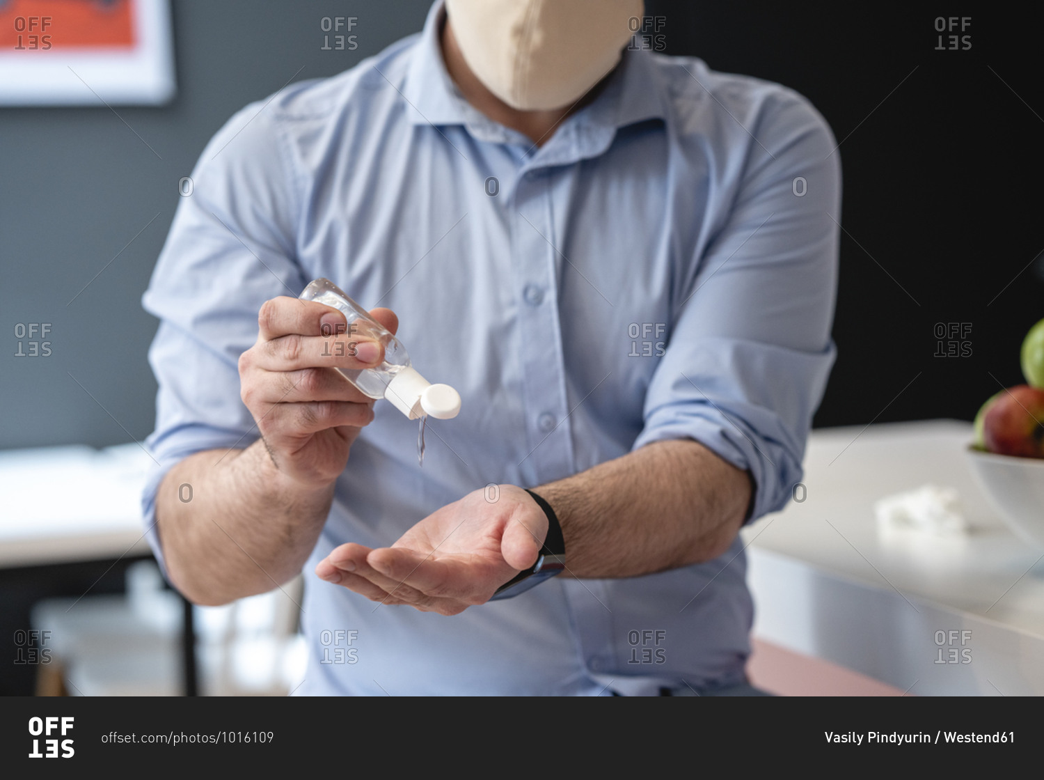 Businessman using hand sanitizer for disinfection at creative office cafeteria