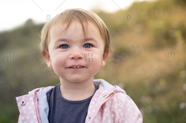 Cheerful little girl with cute ponytails laughing happily while having fun during summer day in nature