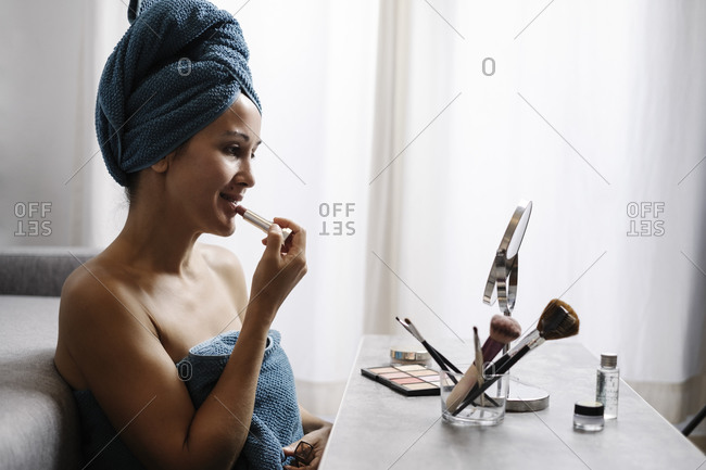 Side view of female applying natural colored lipstick during morning beauty routine