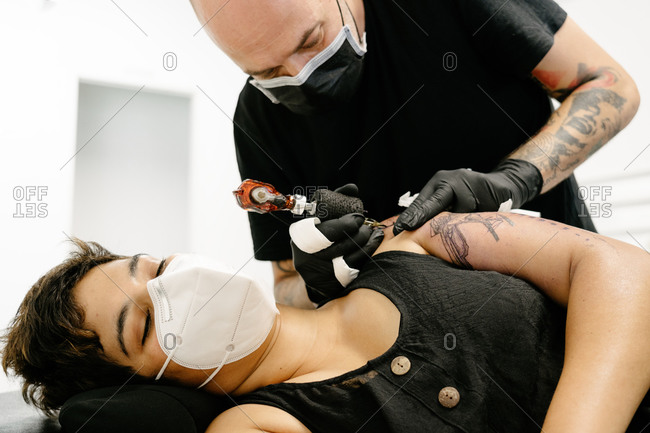 Premium Photo  Close up of professional tattooer artist doing tattoo on  the arm of a young man by machine with black ink