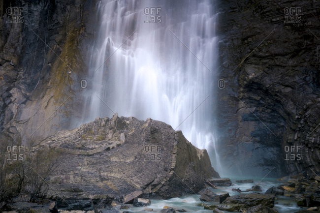Amazing long exposure view of waterfall falling from steep cliff and splashing against rocky ravine