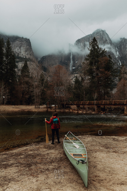 Young female canoeist looking out from riverbank, rear view, Yosemite Village, California, USA