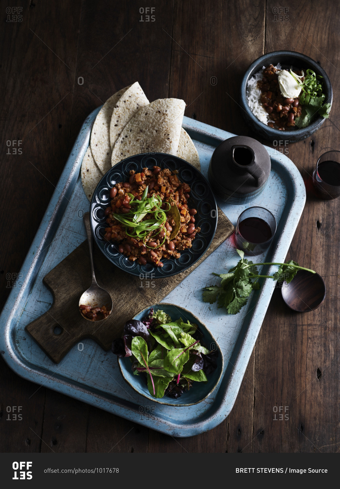 Rustic low key still life with tray of chilli con carne, salad and coffee, overhead view