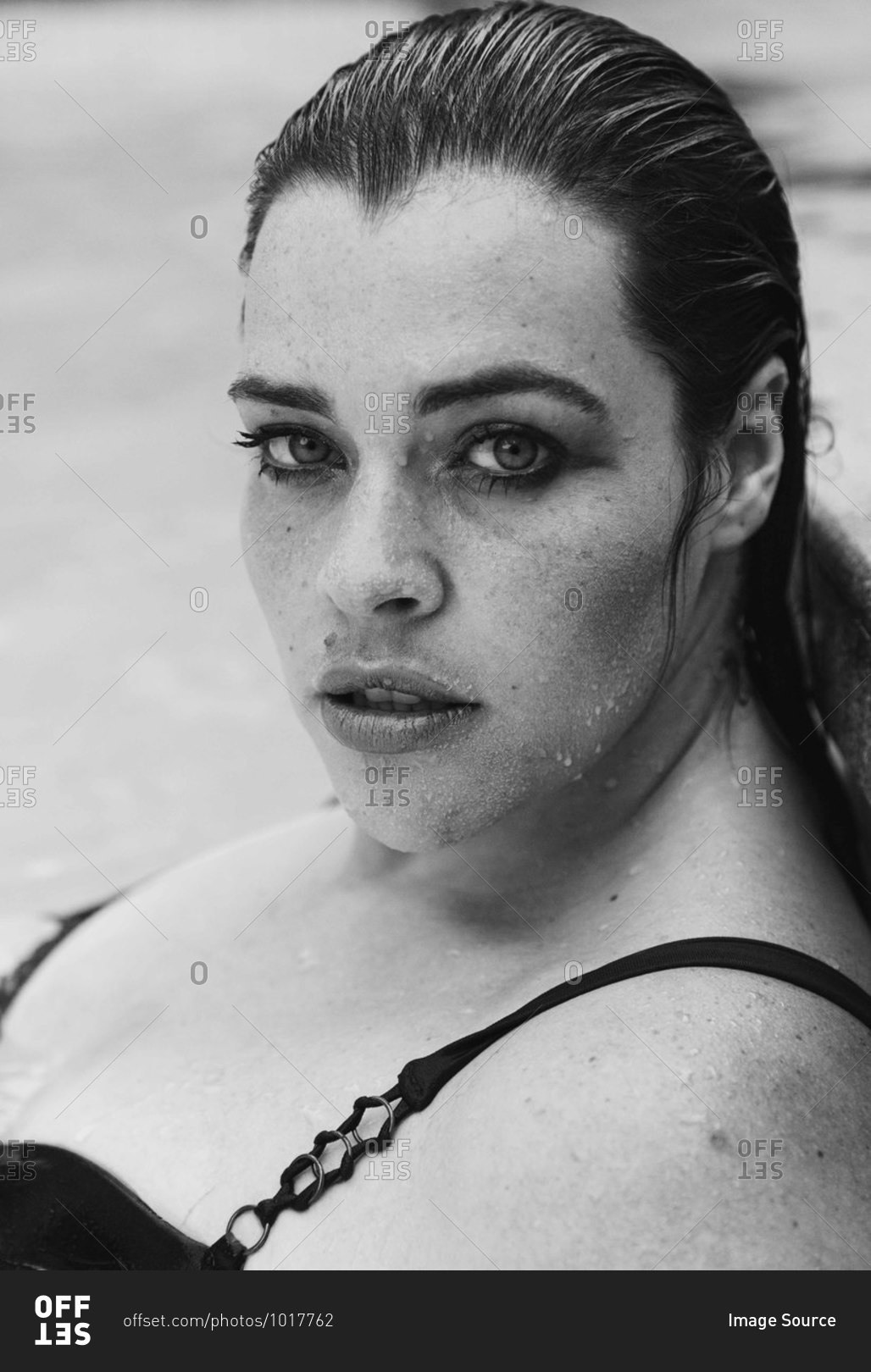 Sultry mid adult woman with wet hair leaning against outdoor swimming poolside, black and white head and shoulder portrait, Cape Town, South Africa