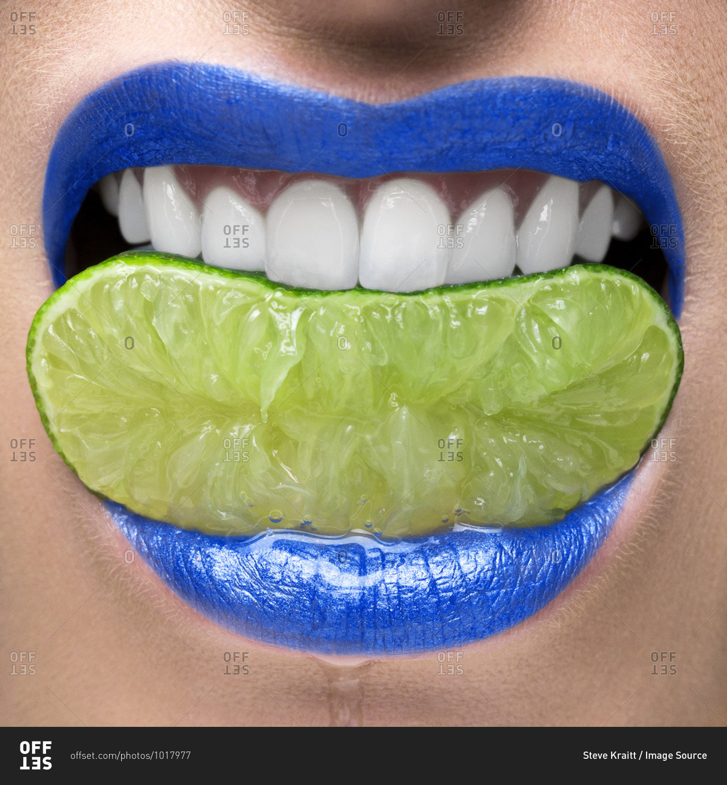 Blue lips biting on lime slice stock photo - OFFSET