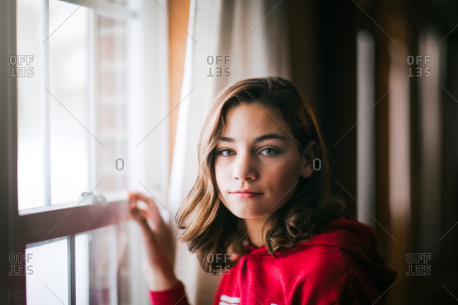 Young girl daydreaming by window at home