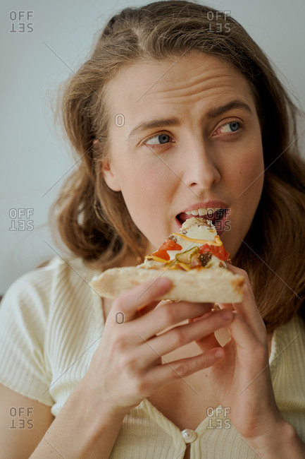 Close up of a blonde woman eating pizza