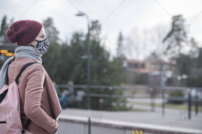 Woman with face mask waiting for public transportation