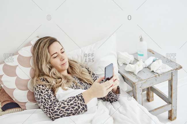 Ill woman in bed using cell phone
