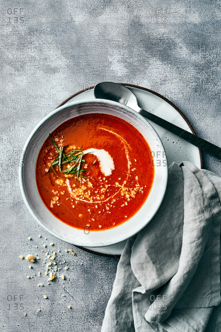 A bowl of creamy tomato soup on gray background
