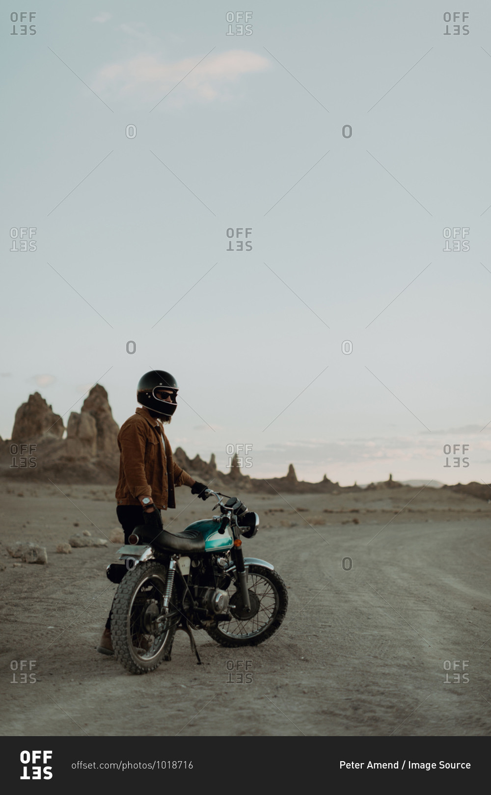 Motorcyclist beside stationary bike in desert, Trona Pinnacles, California, US
