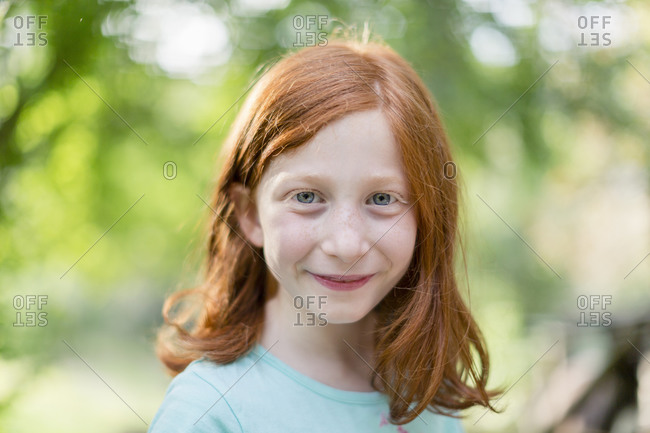 Red haired girl in garden, head and shoulder portrait