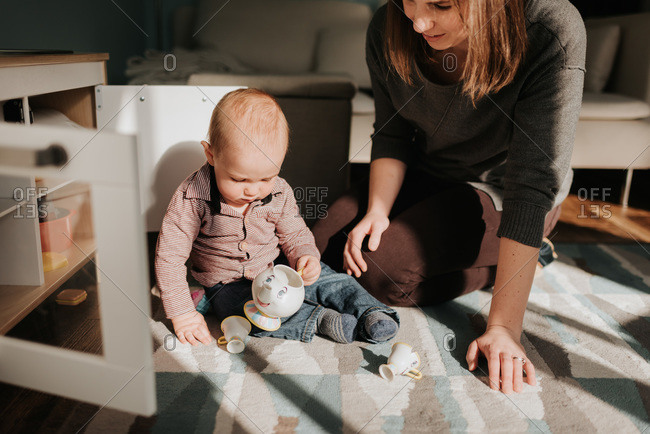 Mother playing with baby son on living room rug