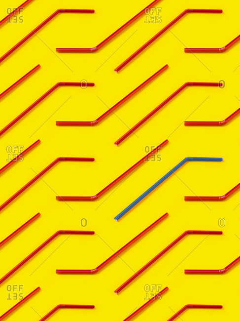 Red and blue straws laid diagonally on yellow background