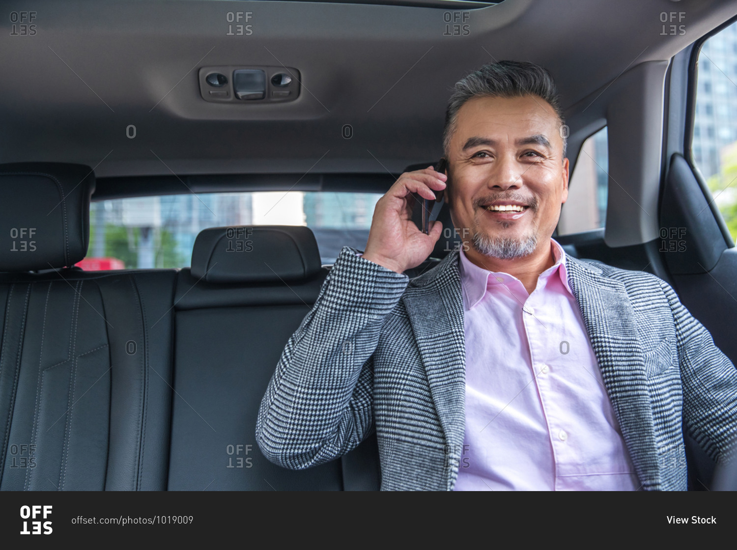 Middle-aged businessman takes a call in his car