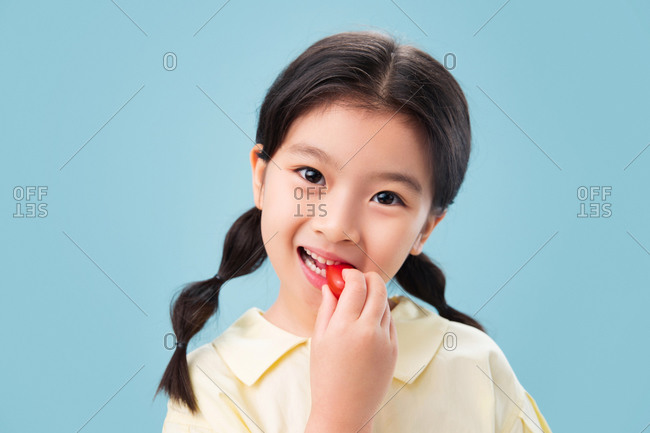 Little girl eating happily eating fruit