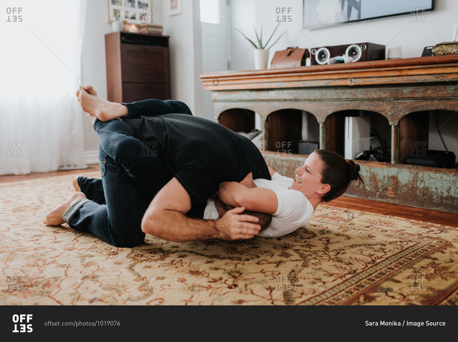 Couple wrestling on carpet at home