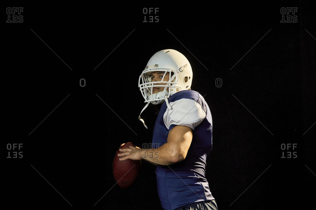 Portrait of quarterback with football, black background