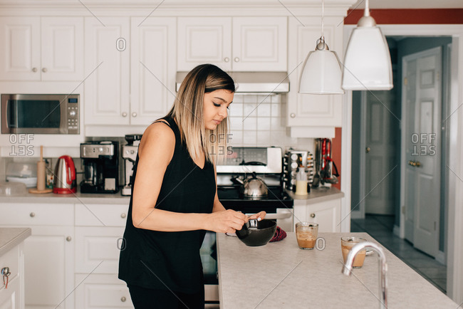 Mid adult woman at kitchen counter with cereal bowl
