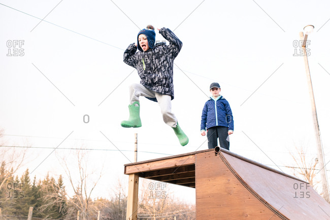 Girl watching brother jump from top of skateboard ramp
