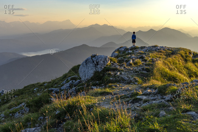 Europe, Germany, Bavaria, Bavarian Alpine foothills, Kochel am See, boy stands on the Benediktenwand and looks at the mountains at sunset