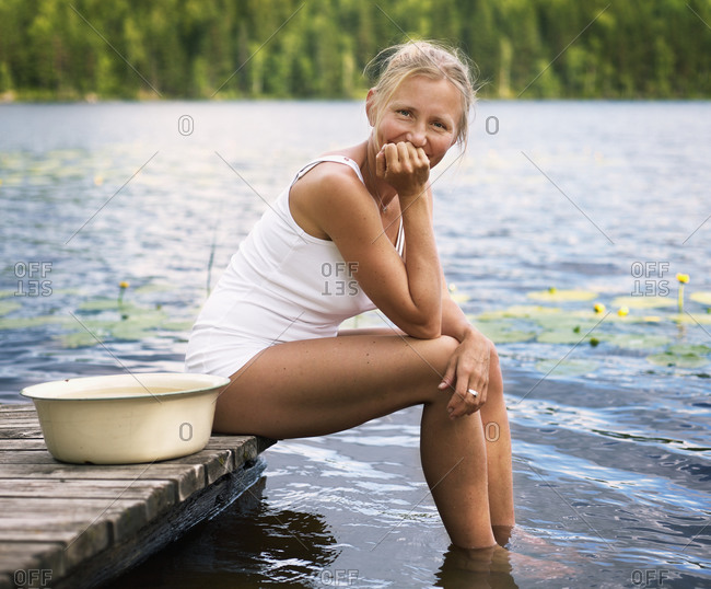Woman sitting on jetty with laundry tub