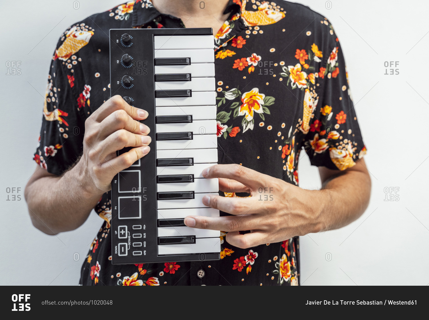 Man playing midi keyboard while standing against wall