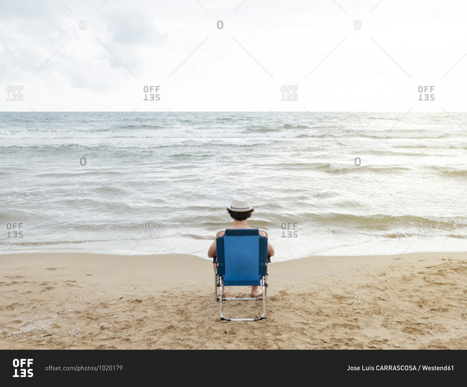 Rear view of man sitting in beach lounger on the beach