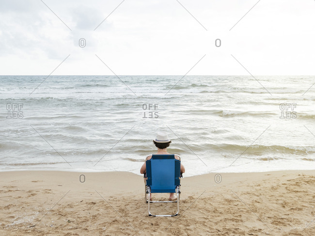 Rear view of man sitting in beach lounger on the beach