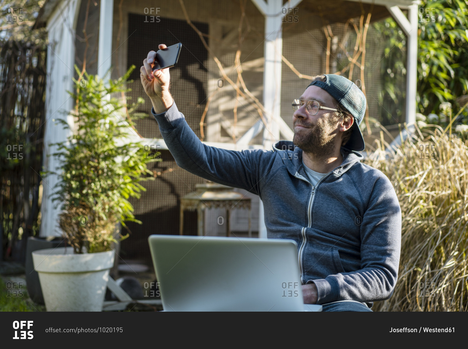 Smiling businessman taking selfie through phone in yard