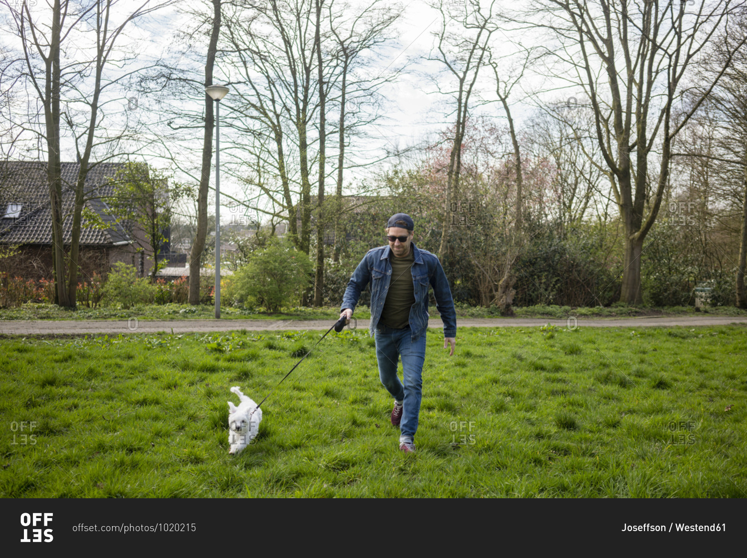 Smiling man running with dog on grass in yard