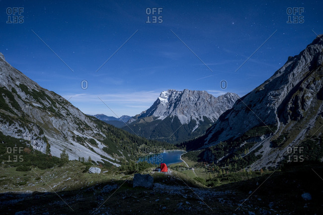 Tent pitched in mountain valley at dusk with Seebensee in background