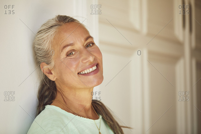 Wrinkled woman against wall at home