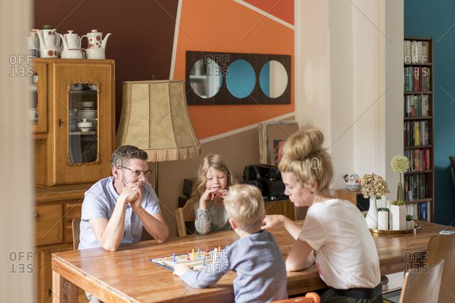 Family playing board game on dining table while sitting at home