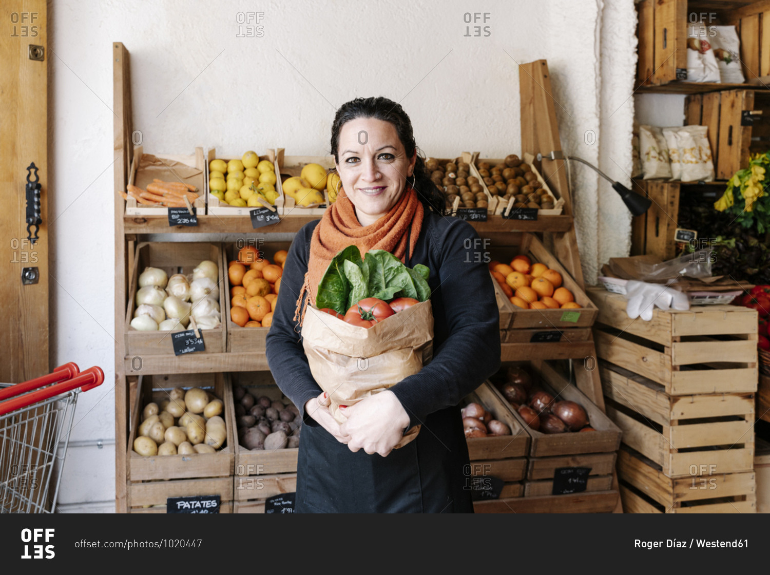 Smiling saleswoman holding vegetable bag at store