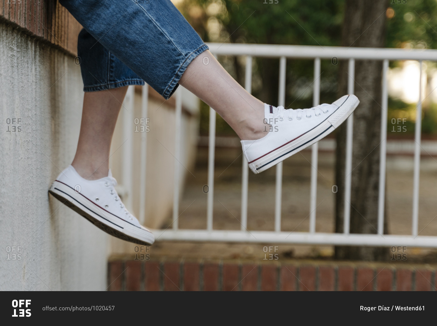 Woman dangling legs while sitting on retaining wall
