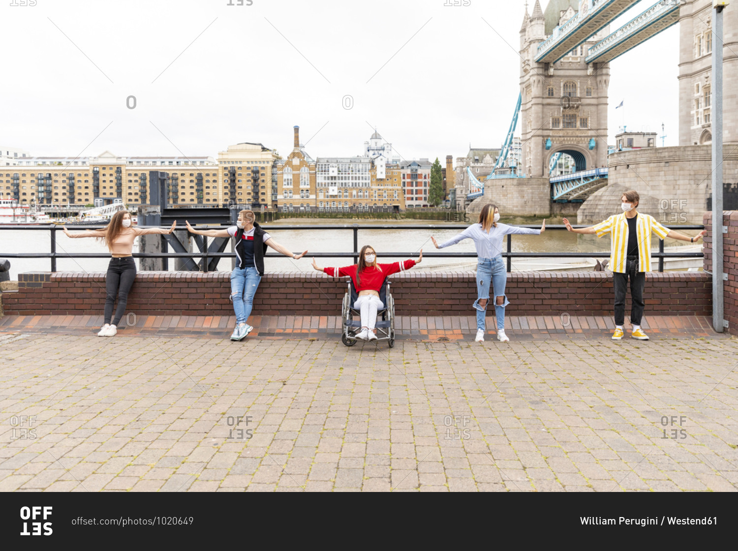 Friends with arms outstretched maintaining safe distance in city- London- UK