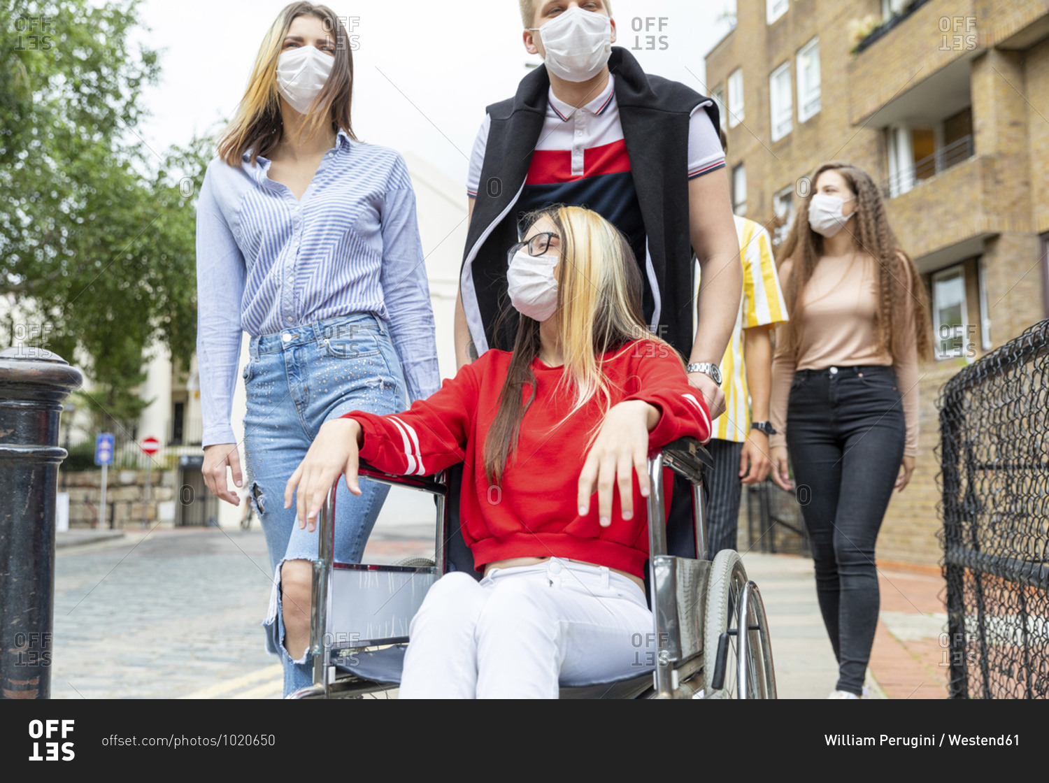 Men and women with disabled female friend wearing masks in city