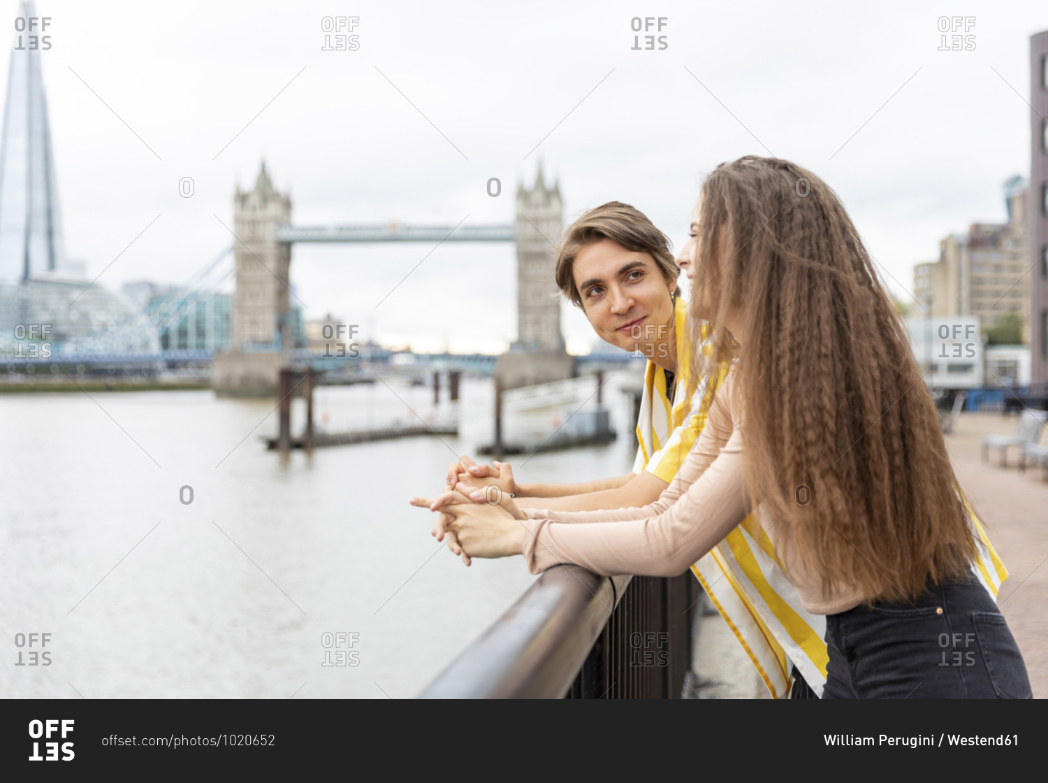 Smiling boyfriend and girlfriend leaning on railing in city- London- UK
