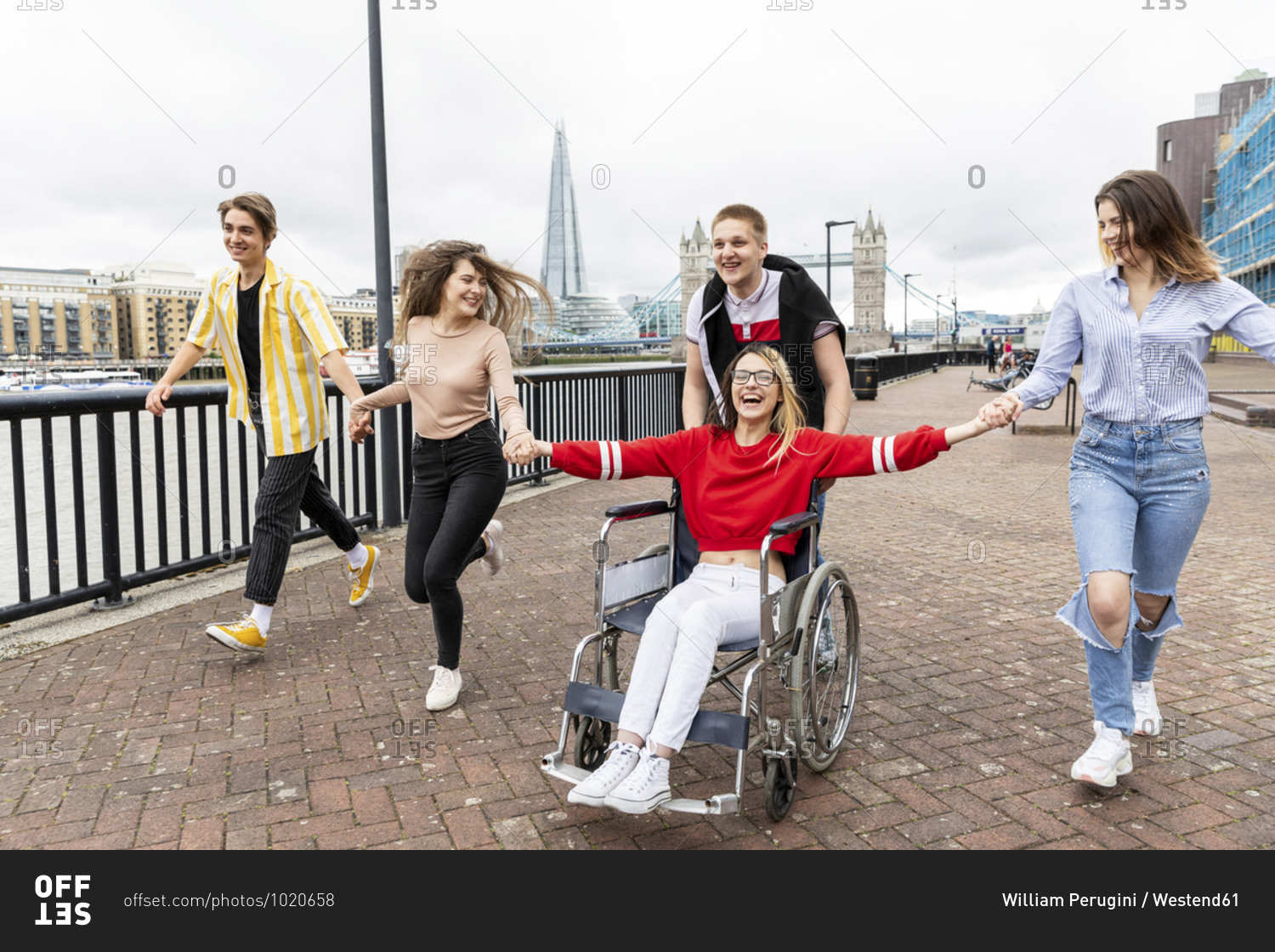 Cheerful men and women with disabled female friend enjoying in city- London- UK
